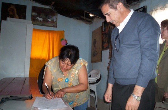 El intendente Sánchez y María Colipe firman el acta que permitirá ceder los terrenos a los poseedores.