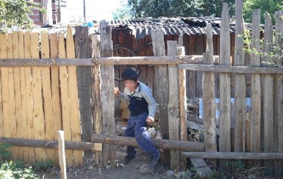 Uno de los hijos de Raquel pasa por un agujero hecho en el cerco de un vecino para llegar a la calle.