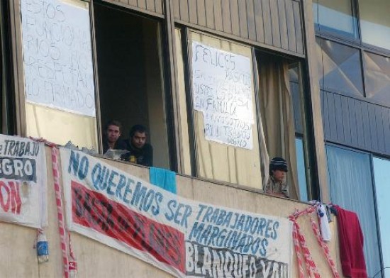Desde las ventanas del edificio y con carteles, los trabajadores buscan que la comunidad se entere de su conflicto.