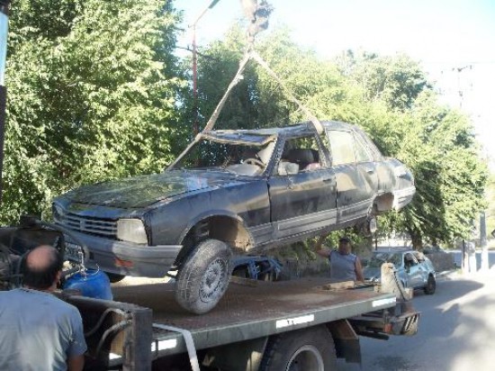 El Peugeot 504 que volcó es trasladado por la policía. 