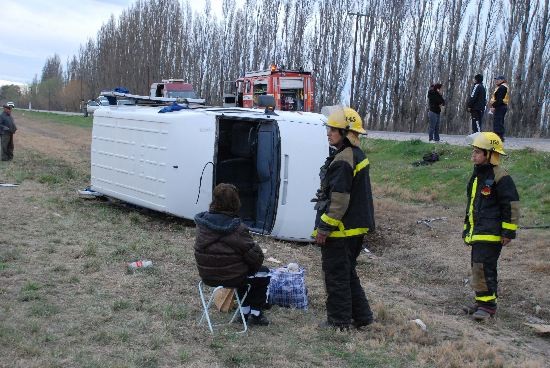 Una de las víctimas es asistida por efectivos de bomberos voluntarios mientras contempla conmocionada cómo quedó la combi. 